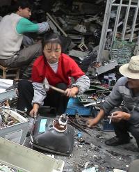 sitting on a pile of broken computers, smashing a CRT monitor with no personal or environmental protection